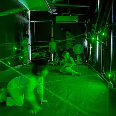 Children navigating green beams in the laser room